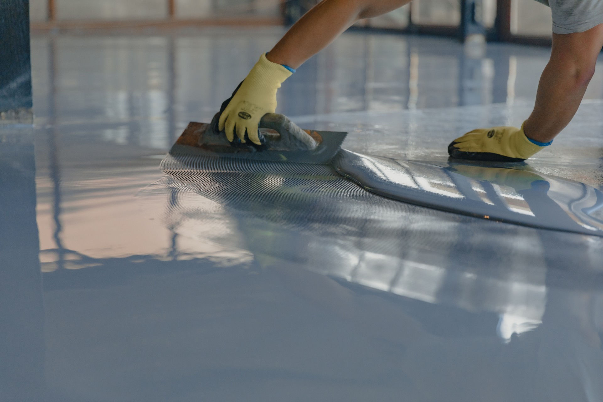 The worker applies gray epoxy resin to the new floor